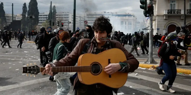 Τέμπη: Μουσικός παίζει κιθάρα εν μέσω των σοβαρών επεισοδίων με βόμβες μολότοφ και χημικά στο Σύνταγμα